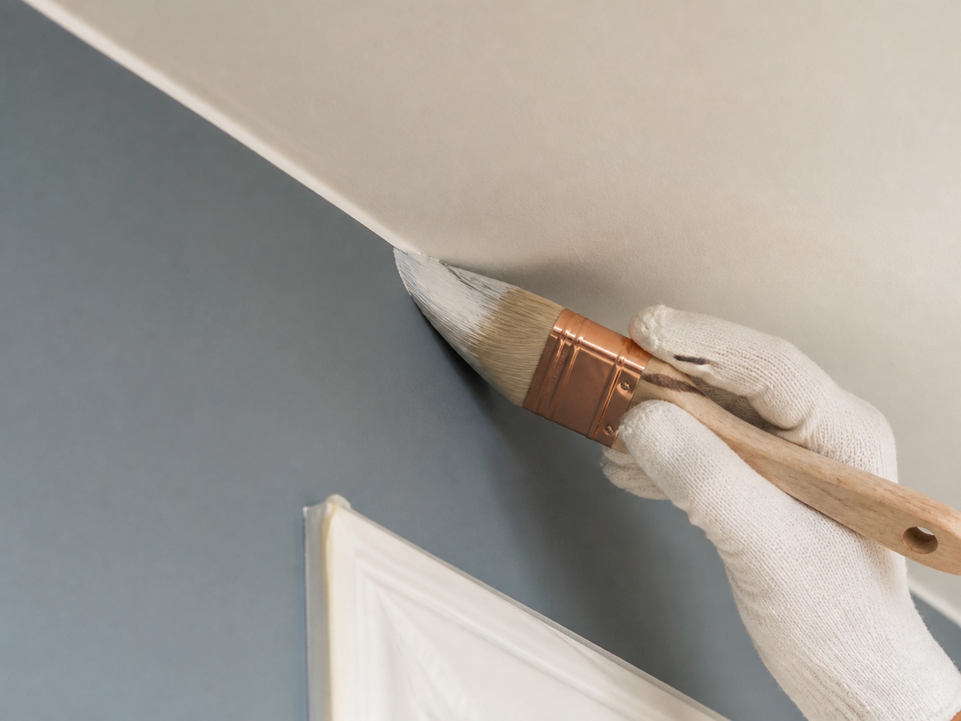 Representative close-up of a painter cutting in a clean, straight edge along ceiling trim